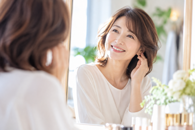 鏡を見ながら笑顔でおしゃれを楽しむ大人の女性